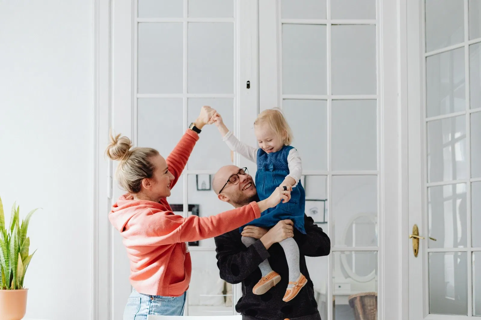 Família loira a brincar em casa com luz natural abundante.