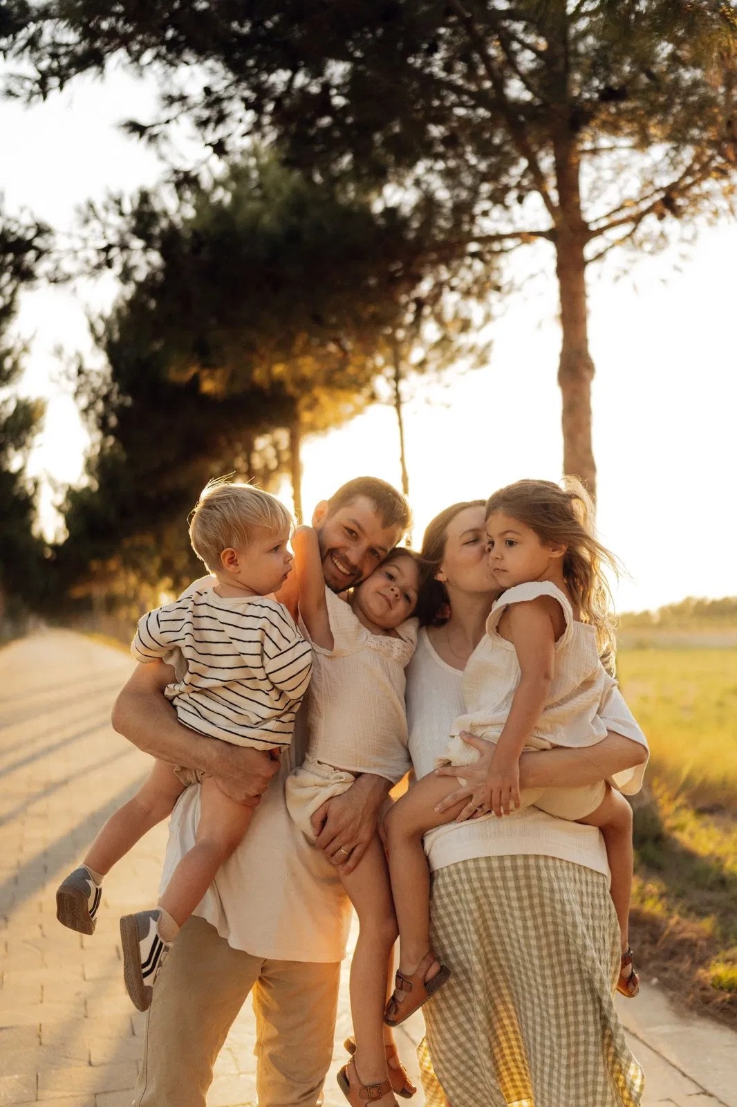 Família loira ao ar livre com luz quente de fim de tarde.