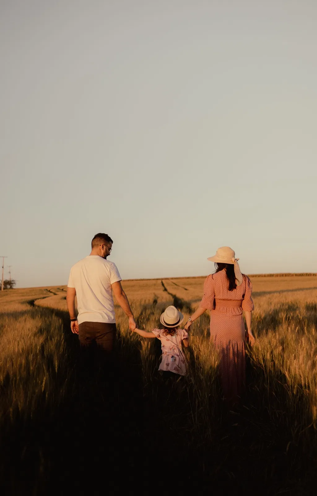 Família a caminhar num campo dourado ao entardecer