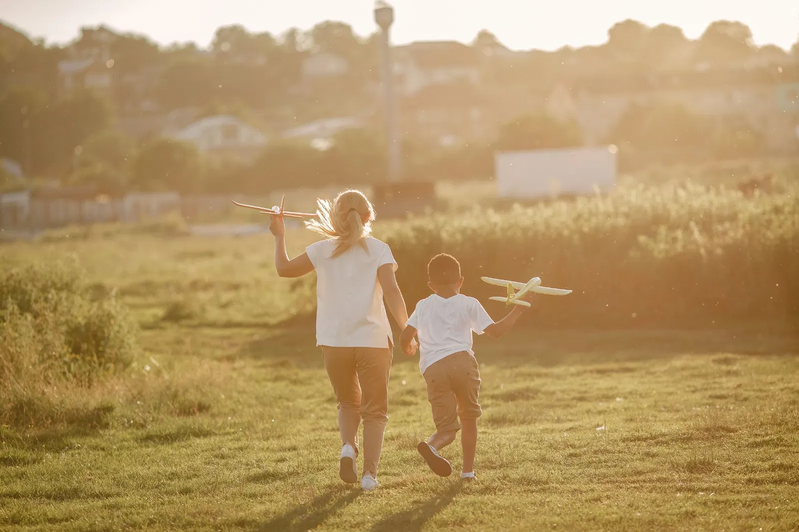 Due bambini che camminano al tramonto in un prato con aeroplani giocattolo in un momento sereno e spontaneo